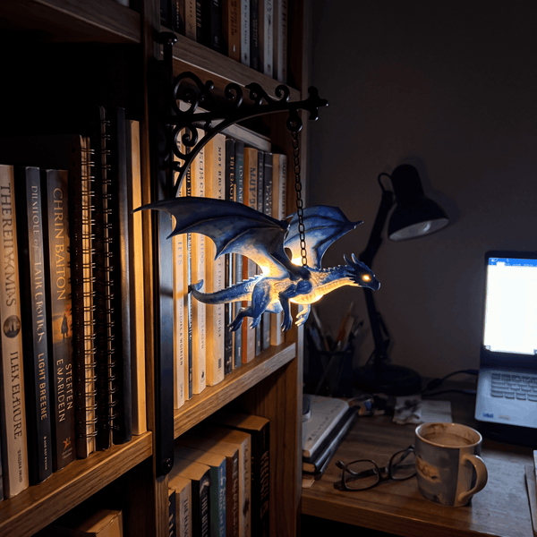 Wyrmglow dragon bookend in a dimly lit study with laptop and books